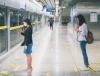 Women physically distancing at train station