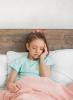 Young girl with headache in bed