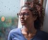 Sad young woman by rainy window