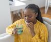 Young woman on couch taking pill
